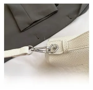 Detailed close-up of premium silver metal hardware hook on white lychee pattern bag