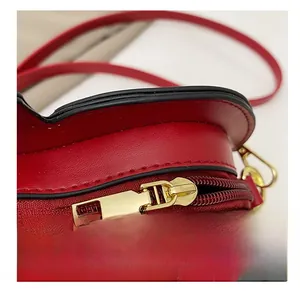 Detailed close-up of smooth golden zipper and texture on red leather heart-shaped bag