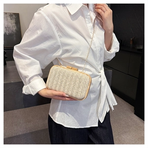 Detail of hand-woven straw box clutch with light wood frame and elegant gold chain strap
