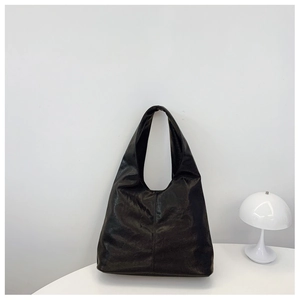 Detail of black large hobo bag with visible stitching beside a white mushroom lamp