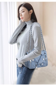 Close-up of blue denim jacket-style crossbody bag with silver studs and zippers