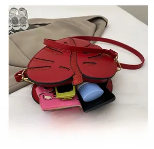Detail view of red leaf-shaped crossbody bag capacity holding a phone and wallet