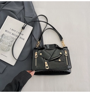 Detail of black moto jacket bag featuring gold zippers, studs, and glossy patent leather