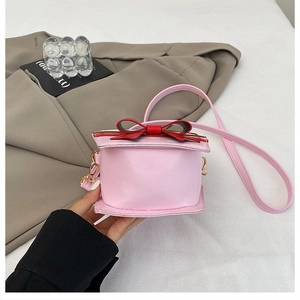 Detail of creative pink strawberry cake crossbody bag with red bow and metallic hardware