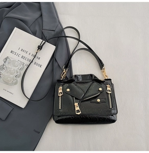 Detail of black biker jacket style crossbody bag with gold zippers and studded texture