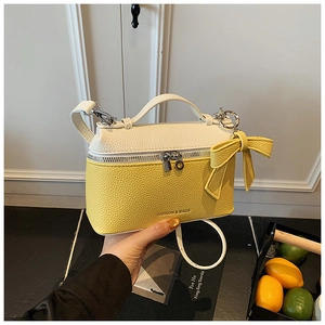 Detail of yellow and white leather handbag with large bow and crossbody strap