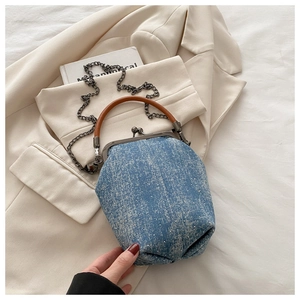 Close-up of retro denim handbag with vintage metal clasp and brown leather handle