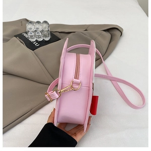 Detail view of pink round crossbody bag with cute 3D ears and a red bow decoration