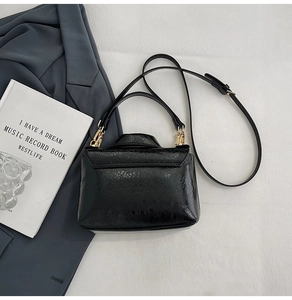 Close-up of black patent leather bag with crackle texture and gold hardware detailing