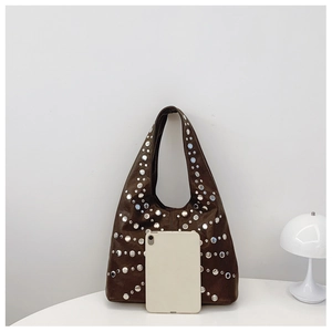 Detail of dark brown tote bag with silver studs and a tablet for size reference