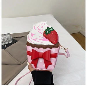 Detail of creative cupcake-shaped crossbody bag with strawberry ornament and red bow