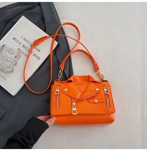 Detailed macro view of orange biker jacket style handbag with gold zippers and studs