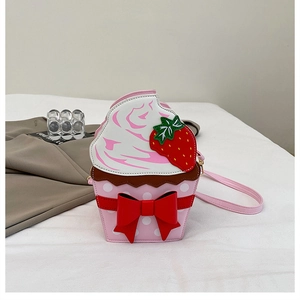 Detail of cupcake shaped crossbody bag with strawberry and red bow decorations