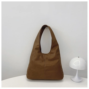 Close-up of brown vintage leather hobo bag with vertical stitching in a home setting