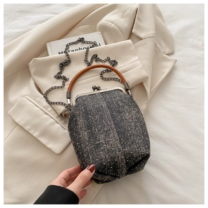 Detail of retro tweed frame bag with brown leather handle and metal chain strap