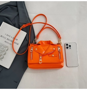 Macro shot of orange biker jacket style crossbody bag with metallic studs and zippers