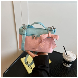 Detail view of pink and blue contrast crossbody bag with leather bow charm and pebble texture