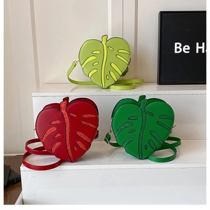 Three Monstera leaf shaped crossbody bags in green and red with glitter leaf vein details