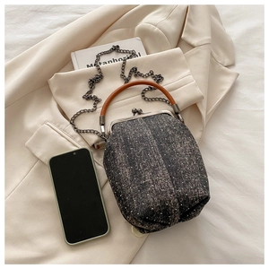 Detail of vintage grey tweed handbag with brown leather handle and metal clasp closure