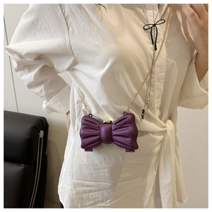 Détail d'un mini sac violet en forme de nœud avec finition métallisée et chaîne dorée