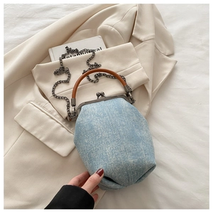 Detail of light blue denim purse with silver polka dots and brown leather handle