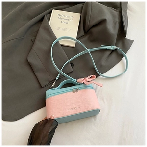 Detail of pink and blue color-block box bag with bow accent and pebble leather texture