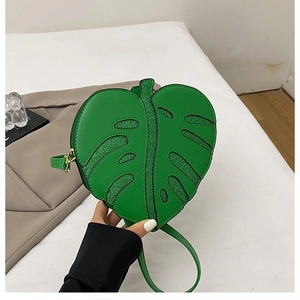 Close-up of green leaf-shaped handbag featuring glitter texture and intricate stitching