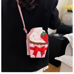 Detail of strawberry cupcake crossbody bag with bow worn by a model in a casual setting
