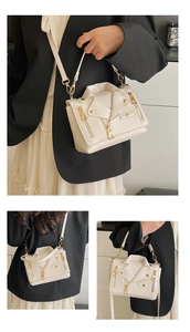 Detail of cream white biker jacket style crossbody bag with gold studs and zippers