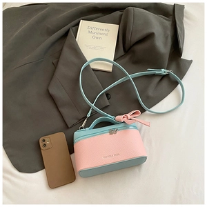 Detail of pink bow and fashion text on blue lychee leather crossbody handbag