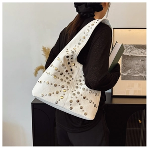 Detail einer weißen Leder-Schultertasche mit dekorativen Silbernieten im Retro-Stil