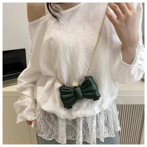Détail d'un mini sac vert en forme de nœud avec finition mate et chaîne dorée