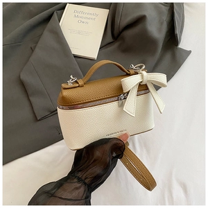 Detail of a mini dual-tone handbag with leather bow accent and adjustable shoulder strap