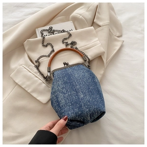 Detail of vintage denim kiss-lock bag with brown handle and silver metal chain strap