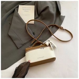 Detail view of a cream and caramel box bag with a sweet bow and leather texture
