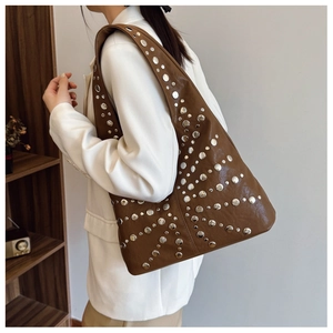 Close-up of retro brown bucket bag with silver metal studs and soft leather texture