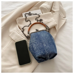 Close-up of retro denim kiss-lock bag with white polka dots and metal chain strap