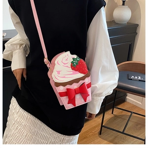 Detail of creative cupcake shaped crossbody bag with strawberry and pink bow decoration