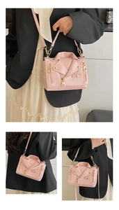 Detailed close-up of pink motorcycle jacket shaped crossbody bag with gold rivet accents