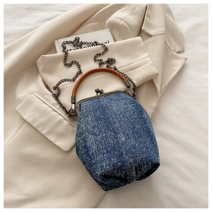 Detail of blue denim doctor bag with retro metal clasp and brown leather handle