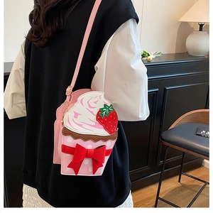 Detail of strawberry cupcake crossbody bag with cream texture and red bow decoration