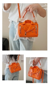 Detail of orange biker jacket bag featuring glossy patent leather and silver metal studs