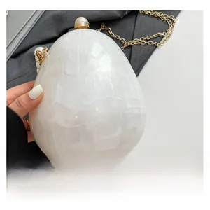 Dettaglio della pochette in acrilico a forma di uovo con texture marmorea e chiusura a perla