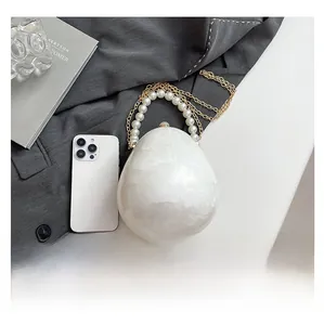 Dettaglio della borsa ovale in acrilico effetto marmo con manico di perle e catena in metallo