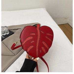 Detail of red leaf-shaped crossbody bag with glitter accents and gold metal hooks