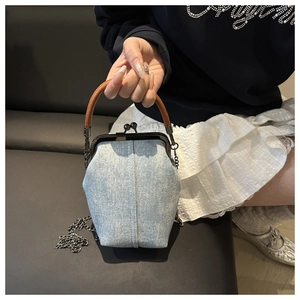 Detail of light blue denim kiss-lock handbag with rhinestone studs and chain strap