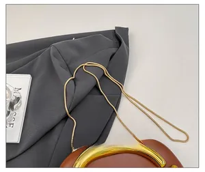 Detail of elegant gold snake chain strap on brown leather evening clutch bag