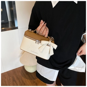 Detail of small two-tone handbag with lychee texture and a large bow charm