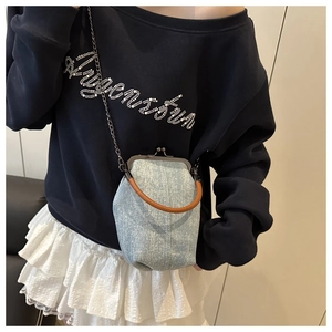 Light blue denim crossbody bag with rhinestones and brown top handle on a model