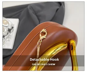 Detail of the golden detachable hook and sturdy handle on a brown leather clutch